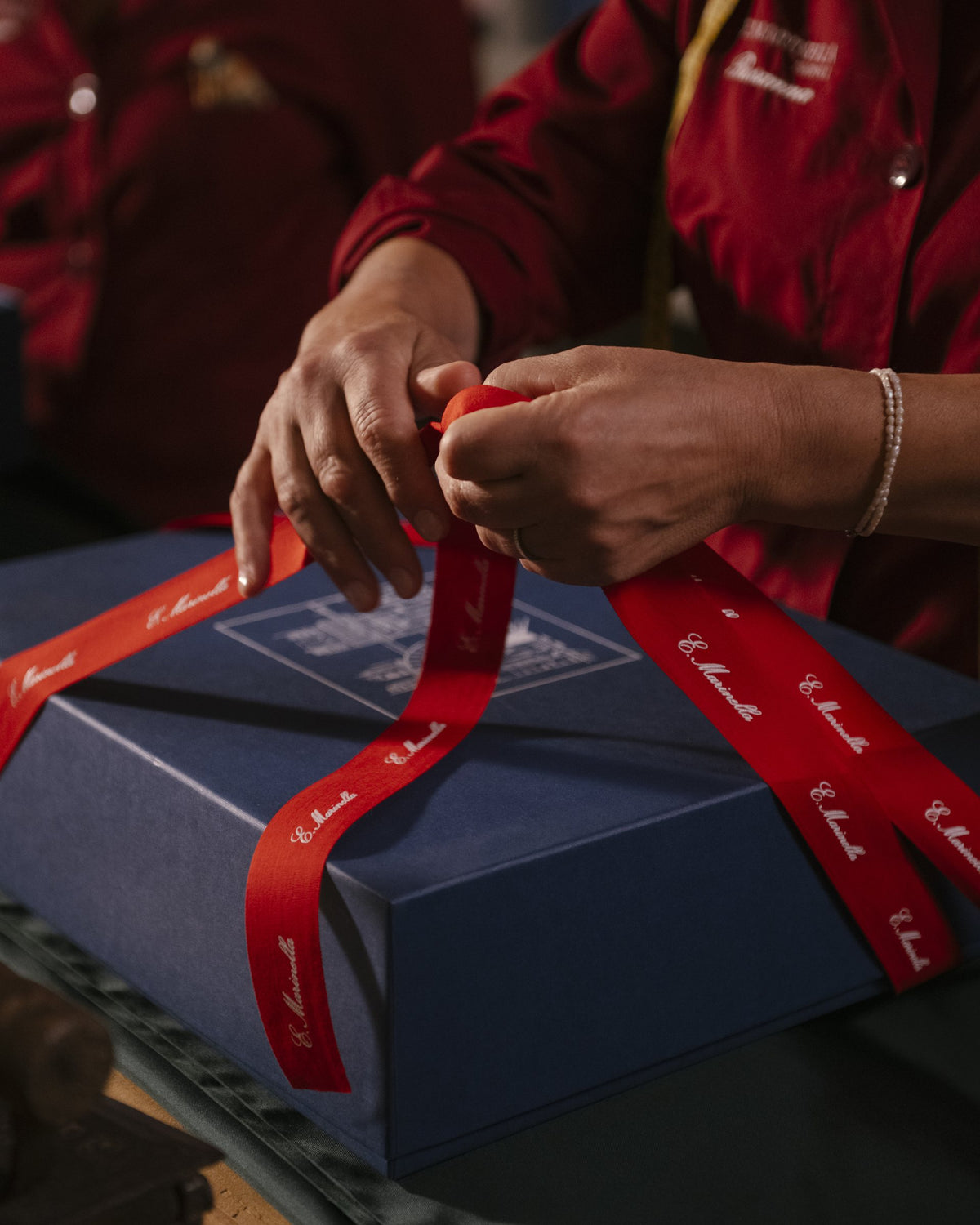 Una sarta chiude una box con il nastro della Maison