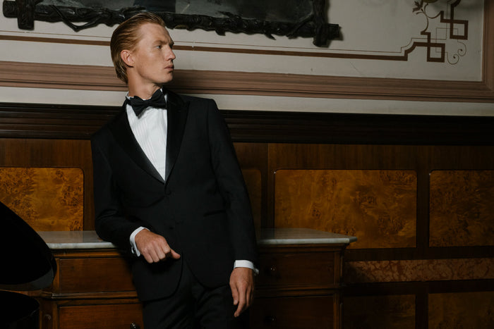 Uomo che indossa un completo Black Tie E. Marinella con smoking nero, papillon in seta e camicia da cerimonia